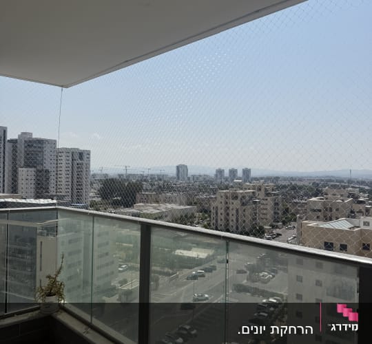 רשת נגד יונים מותקנת במרפסת עם מעקה זכוכית